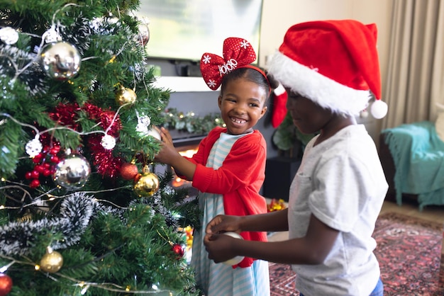 Photo african american siblings spending time together and decorating christmas tree. christmas, family time and celebration concept.