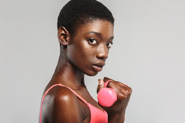 african american sportswoman doing exercise with dumbbells isolated over white wall