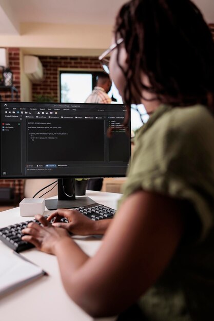 ボーイフレンドが自宅のリビングルームでリラックスしている間、ソースコードを書くプログラミングを学ぶアフリカ系アメリカ人の学生。フリーランスのソフトウェア開発者は、パーソナル コンピューターを使用してリモート デバッグ アルゴリズムに取り組んでいます
