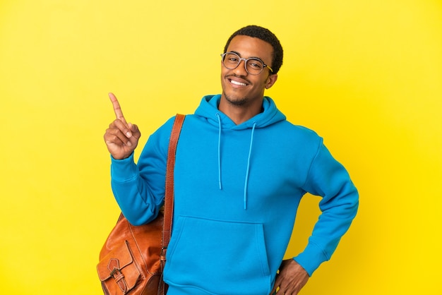 African American student man over isolated yellow background showing and lifting a finger in sign of the best