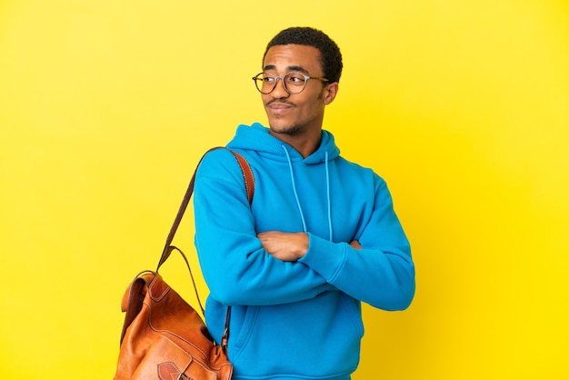 Афро-американский студент человек на изолированном желтом фоне со скрещенными руками и счастливым