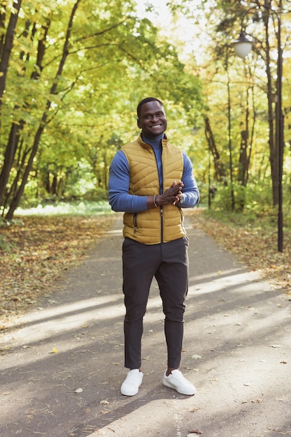 African american student walking in the park in autumn season.