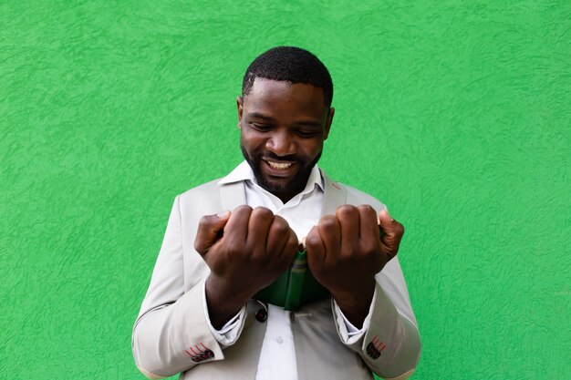 The African American student with a book on a green background