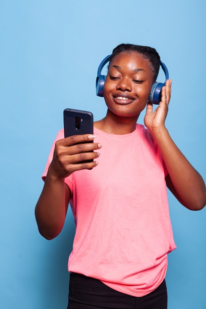 African american student with headphones holding smartphone