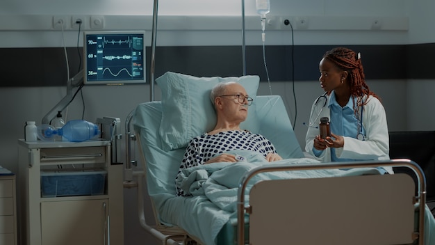 african american surgeon showing bottle of pills to patient