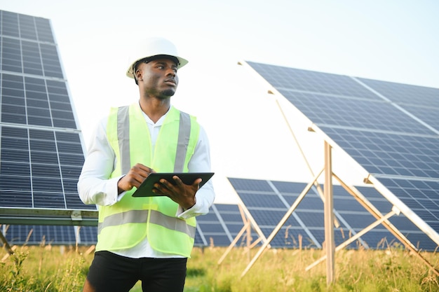 アフリカ系アメリカ人技術者太陽光パネルのメンテナンスをチェックする 太陽光発電所の黒人エンジニア