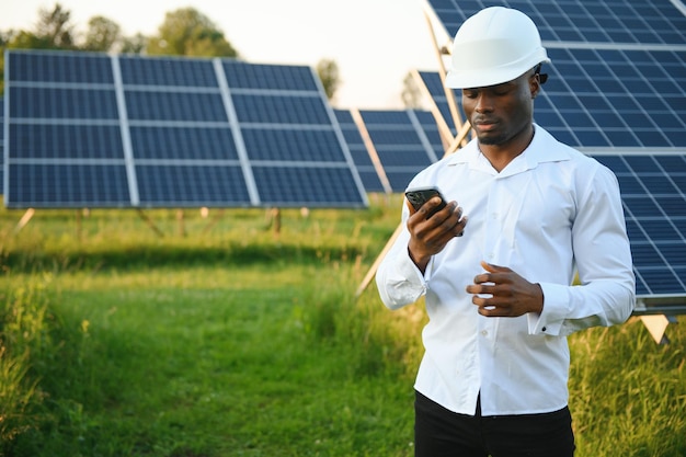 アフリカ系アメリカ人技術者太陽光パネルのメンテナンスをチェックする 太陽光発電所の黒人エンジニア