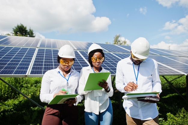 African american technician checks the maintenance of the solar panels. Group of three black engineers meeting at solar station.