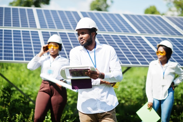 African american technician checks the maintenance of the solar panels Group of three black engineers meeting at solar station