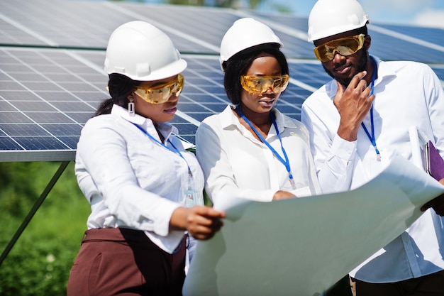 African american technician checks the maintenance of the solar panels Group of three black engineers meeting at solar station