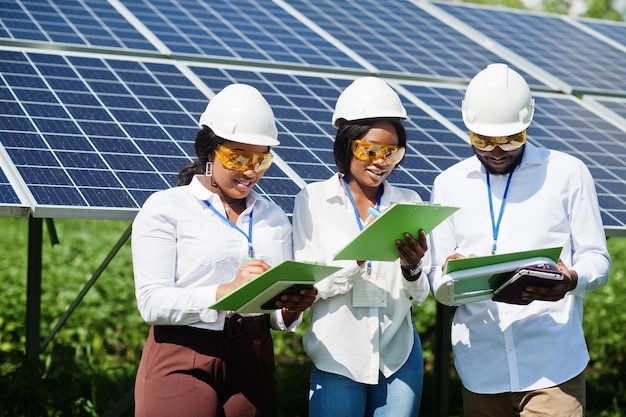 African american technician checks the maintenance of the solar panels Group of three black engineers meeting at solar station