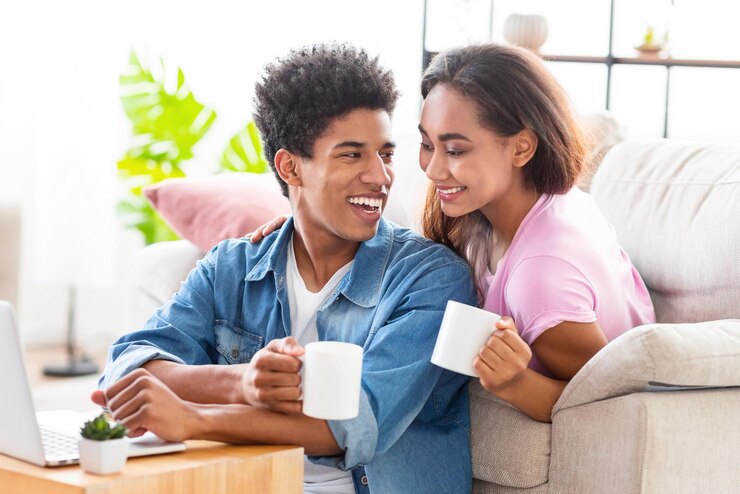 Photo african american teen couple is sitting on a couch in a living room the guy is looking at the girl