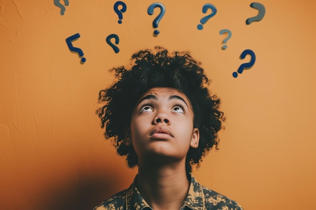 African American teen gazing upwards at floating question marks orange backdrop