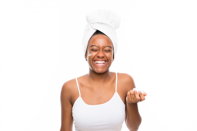 African American teenager girl with moisturizer over isolated white wall