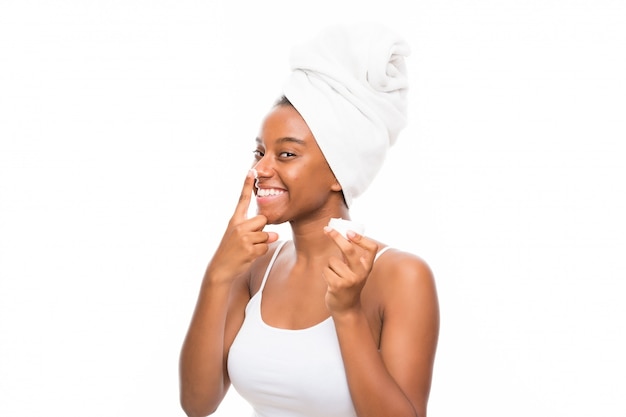 African American teenager girl with moisturizer over white wall