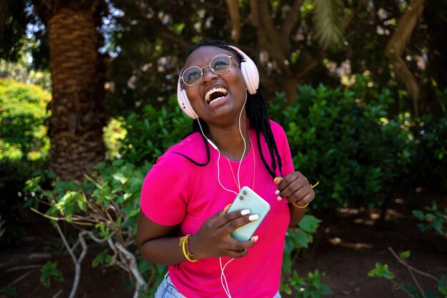 African American teenager listening to music with headphones and mobile