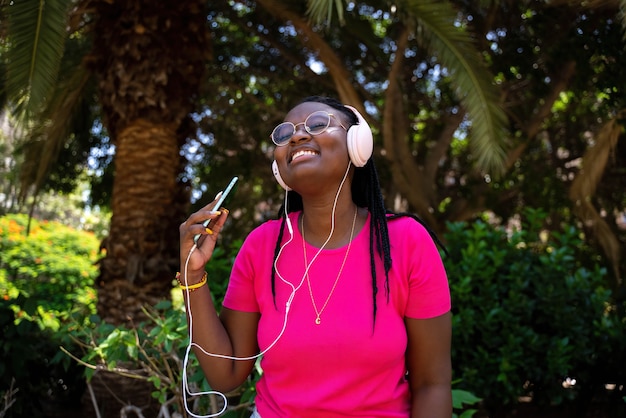 Adolescente afroamericano che ascolta musica con cuffie e cellulare