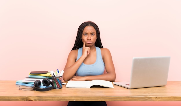 African American teenager student girl with long braided hair in her workplace Looking front