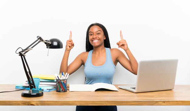 African American teenager student girl with long braided hair in her workplace pointing up a great idea