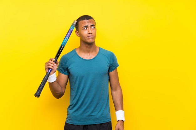 African american tennis player man having doubts and with confuse face expression