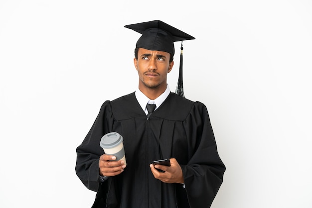 African American university graduate man over isolated white background holding coffee to take away and a mobile while thinking something