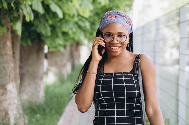 African American vrouw in een jurk heeft buiten plezier en praat via de telefoon