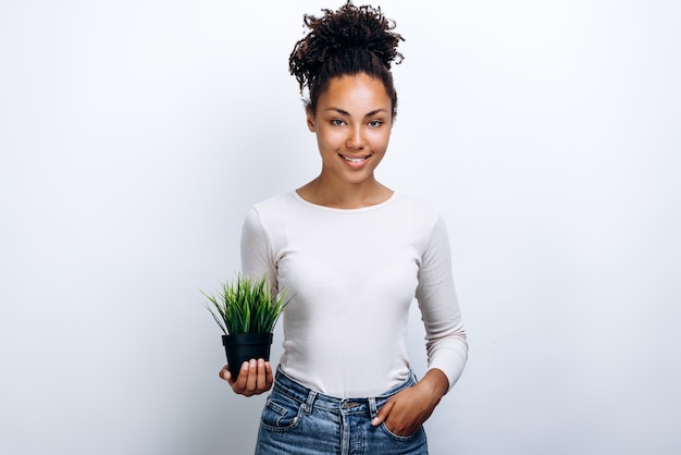 African American vrouw in een witte blouse met een kamerplant