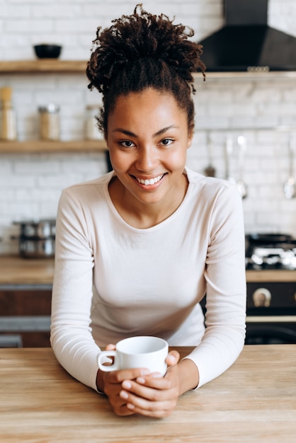 African American vrouw met een kopje koffie in de keuken