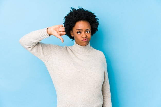 African American vrouw van middelbare leeftijd tegen een blauwe muur geïsoleerd met een afkeer gebaar, duimen naar beneden. Meningsverschil concept.