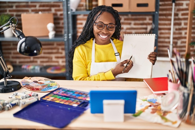 African american woman artist having online paint lesson at art studio