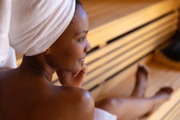 Photo african american woman in a bathrobe relaxing in the sauna. spa, wellness and relaxation concept