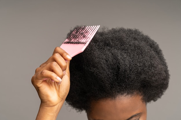 Photo african american woman combing curly hair ethnic female hand hold hairbrush at wavy afro hairdo