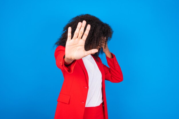 African American woman covers eyes with palm and doing stop gesture tries to hide