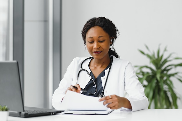 African American woman doctor working at her office online using portable inormation device