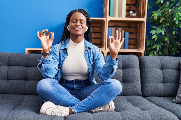 African american woman doing yoga exercise sitting on sofa at home