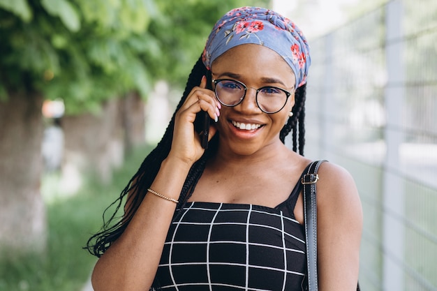 African American woman in a dress has fun outside and talks by phone