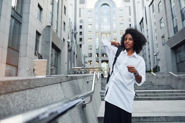 African american woman in good clothes is outdoors in the city at daytime