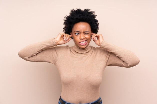 Fondo isolato donna afroamericana frustrata e che copre le orecchie