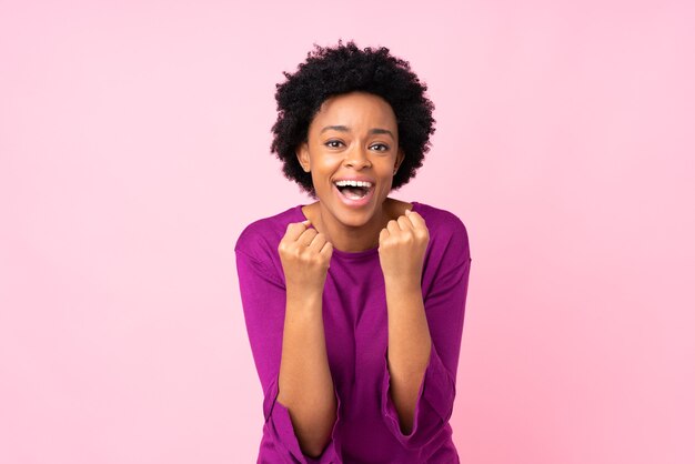 African american woman on isolated pink celebrating a victory in winner position