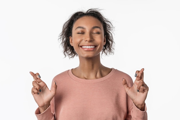 African american woman over isolated white background with fingers crossing