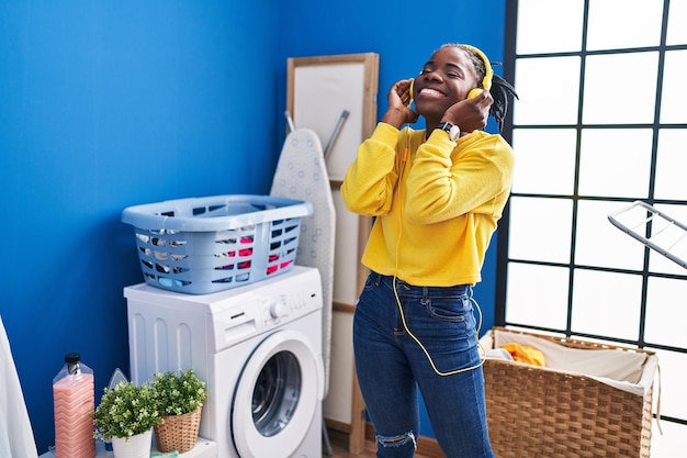 African american woman liatening to music waiting for washing machine at laundry room