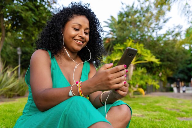 公園で音楽を聴いているアフリカ系アメリカ人の女性