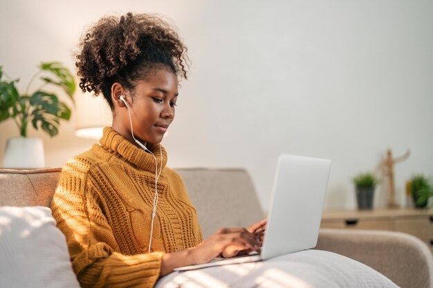 African american woman listening to music relaxed with on laptop at home