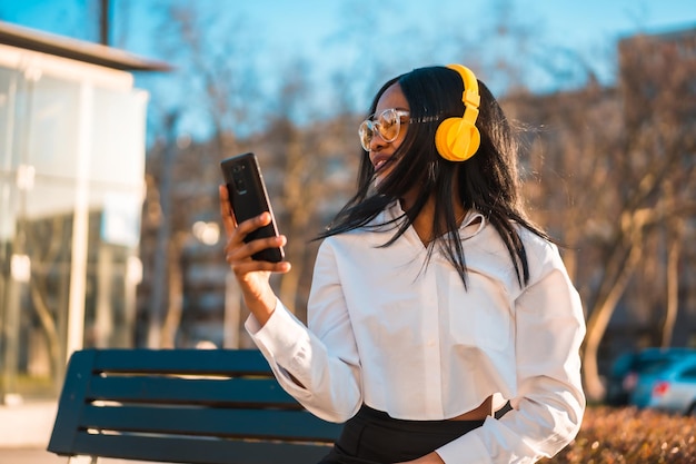 African american woman listening to music with headphones at sunset in the city copy paste