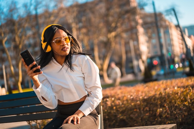 African american woman listening to music with headphones at sunset in the city copy paste