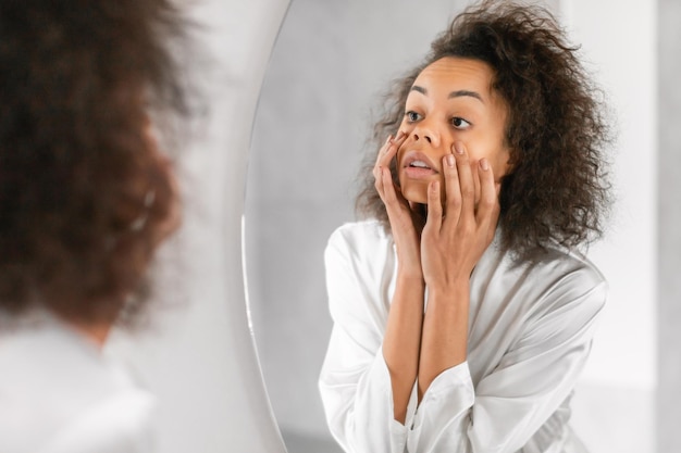 african american woman looks upset touching her tired face indoors