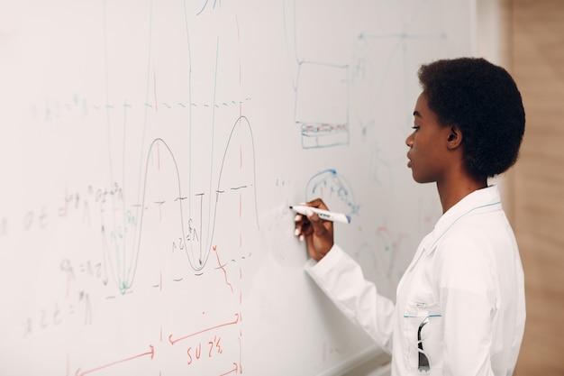 Photo african american woman math teacher writing on blackboard