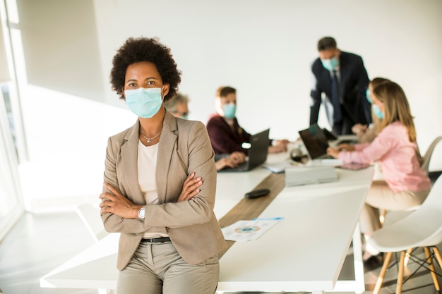 Donna afro-americana in ufficio indossare maschera come protezione dal coronavirus