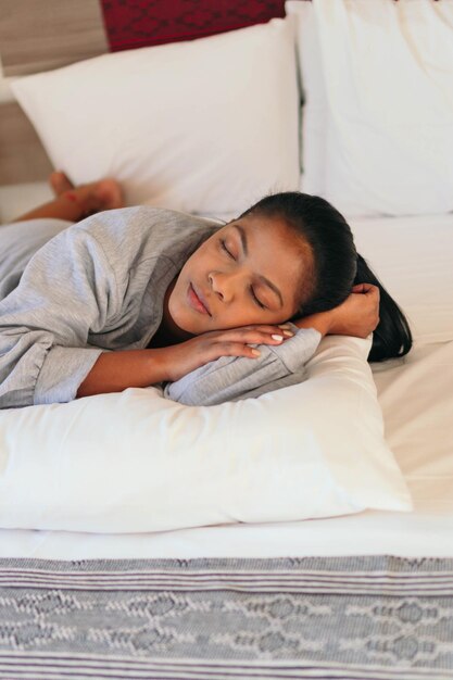 African-American woman in pajamas sleeping in her bedroom