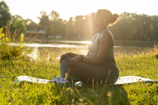 Foto donna afroamericana che pratica la meditazione al parco